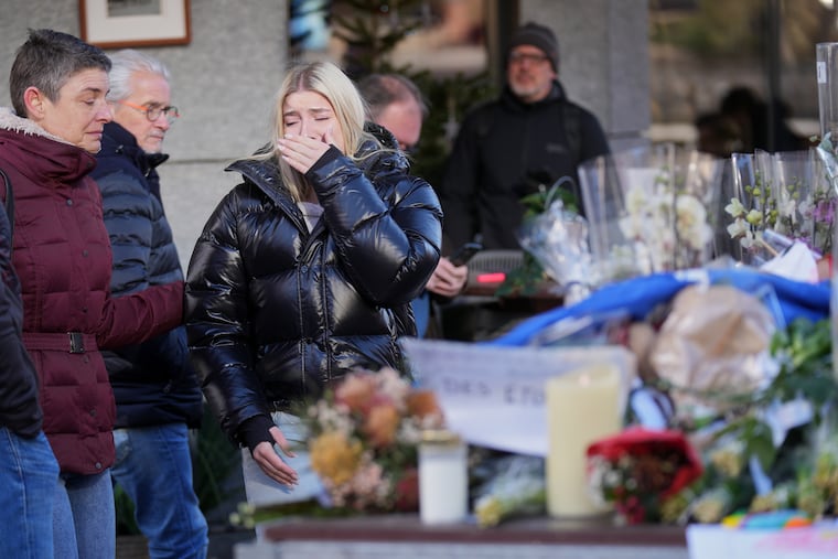 People bring flowers near the sealed off Le Constellation bar at the ski resort of Crans-Montana in Switzerland.