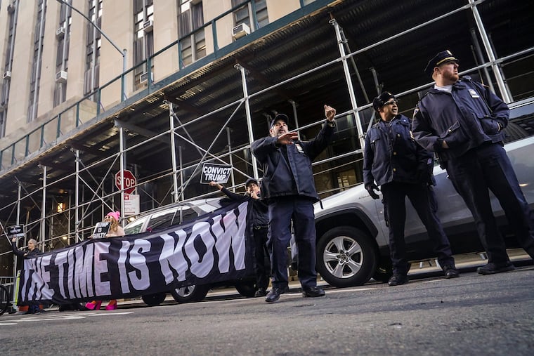 Demonstrators unveil a banner outside Manhattan's district attorney office, supporting a grand jury vote to indict former President Donald Trump on March 30, 2023, in New York.