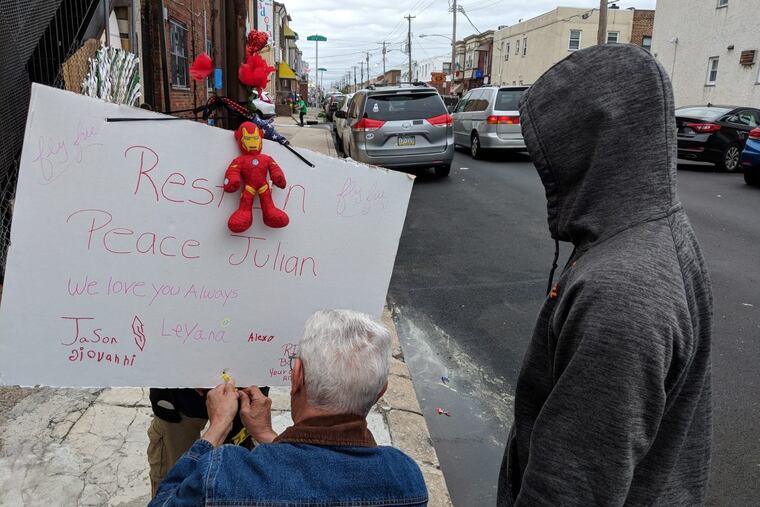A man helps to secure a sign in honor of an 11-year-old boy who was killed by a hit-and-run driver Friday in South Philadelphia