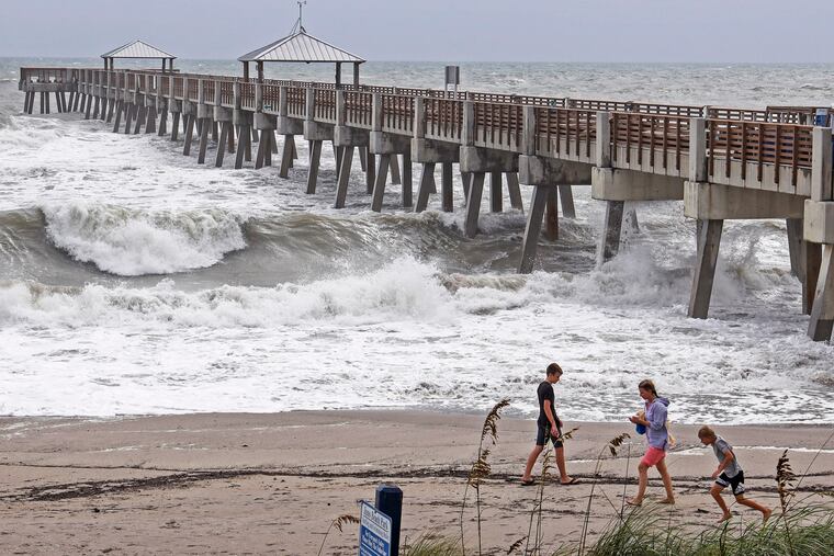 Beach goers get a closer look of the waves crashing against the Juna Beach Pier in Juno Beach, Fla., Monday, Sept. 2, 2019, as Hurricane Dorian crawls toward Florida, while the storm continues to ravage the Bahamas. (Carl Juste/Miami Herald via AP)