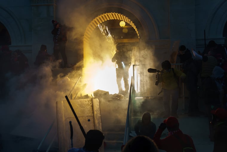 Police clear a doorway that was previously under attack with what appears to be a flash grenade and tear gas at the capital building on Wednesday in Washington, DC. The United States Capitol Building was breached by thousands of Pro Trump supporters.