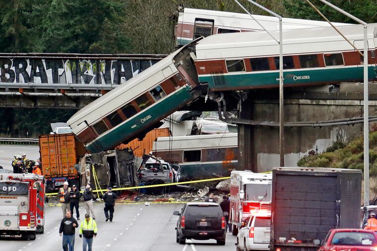 FILE - In this Dec. 18, 2017, file photo, cars from an Amtrak train lay spilled onto Interstate 5 alongside smashed vehicles as some train cars remain on the tracks above in DuPont, Wash. Federal safety investigators are expected to present their findings Tuesday, May 21, 2019, on the Amtrak train derailment south of Seattle that killed three people and injured dozens. (AP Photo/Elaine Thompson, File)