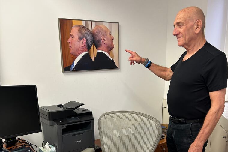 Former Israeli Prime Minister Ehud Olmert points to a photo of him and President George W. Bush head to head (to see which of them was taller) in his office in Tel Aviv, Israel