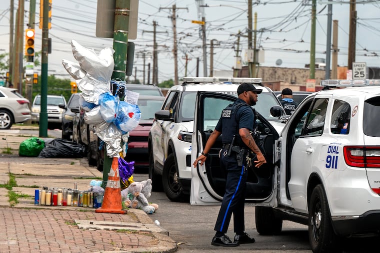 A memorial from a car accident earlier this summer is on the street as police officers remain on the scene Sunday morning, Aug. 16, 2026 at Elmwood Avenue and South 73rd Streets where earlier an off-duty Philadelphia police officer died after he was shot at an after-hours lounge near the intersection.