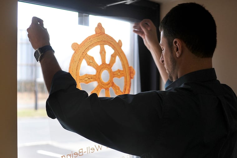 Andrew Assini checks the fit of his door sign, before installing the clear plastic sheet while setting up his own addiction treatment practice in Glassboro December 29, 2014. ( TOM GRALISH / Staff Photographer )