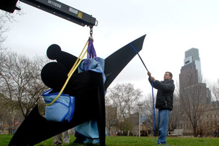 Eric McDade with Crozier Fine Arts helps remove the Alexander Calder sculpture "Three Discs, One Lacking (1968)," from it's place at 22nd and the Parkway on Wednesday. (Tom Gralish / Staff Photographer)