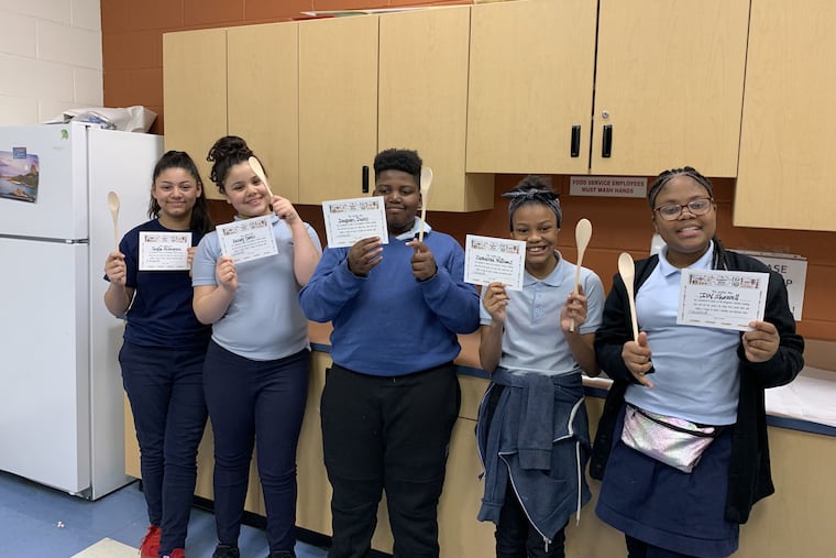 Jayla Velasquez, Rosary Torres, Daquan Davis, Jazziarah Williams, and Ivy Showell display their certificates of completion and wooden spoons during the final meeting of the spring 2019 My Daughter's Kitchen cooking program at Feltonville School of Arts & Sciences.