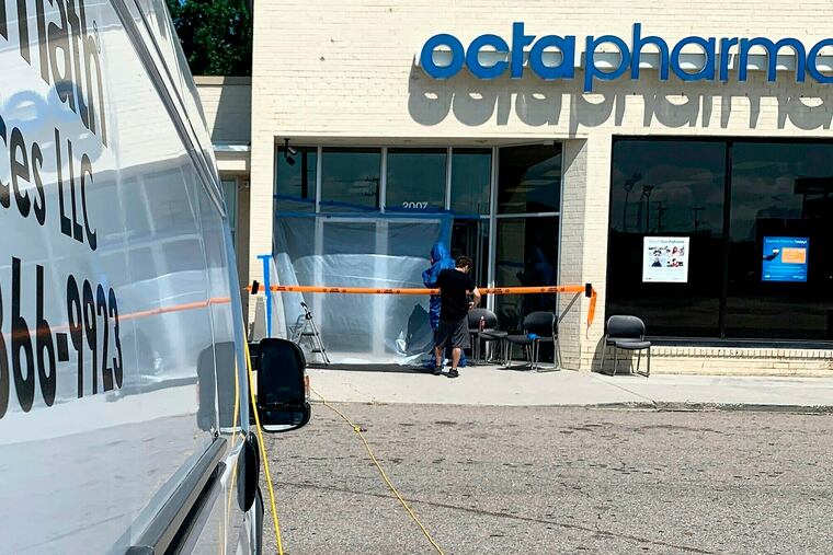 A crew from Aftermath Services in Richmond places tarp over the entrance to Octapharma Plasma in Petersburg, Va., Friday, July 5, 2019. The crew had sealed the doors and was preparing to enter the business where, the day before, a 20-year-old Petersburg man is alleged to have attacked customers with an unidentified cutting weapon. (Bill Atkinson / The Progress-Index via AP)