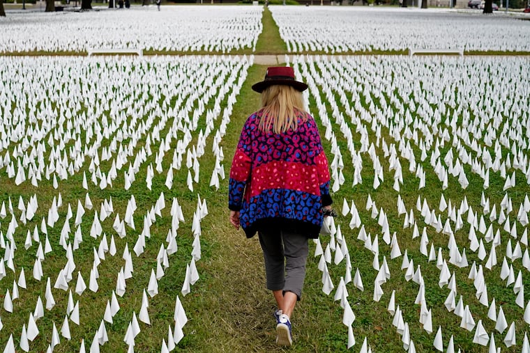 Artist Suzanne Brennan Firstenberg walks among thousands of white flags planted in remembrance of Americans who have died of COVID-19 near Robert F. Kennedy Memorial Stadium in Washington.