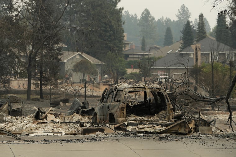 A vehicle and structure are burned on N. Skyline Dr. after a wildfire, Sunday, Aug. 2, 2026, in Spokane, Wash.