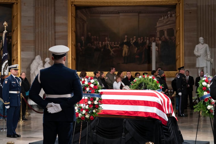 Mourners look at the flag-draped casket of former President Jimmy Carter as he lies in state in the U.S. Capitol on Tuesday. Carter died Dec. 29 at the age of 100.