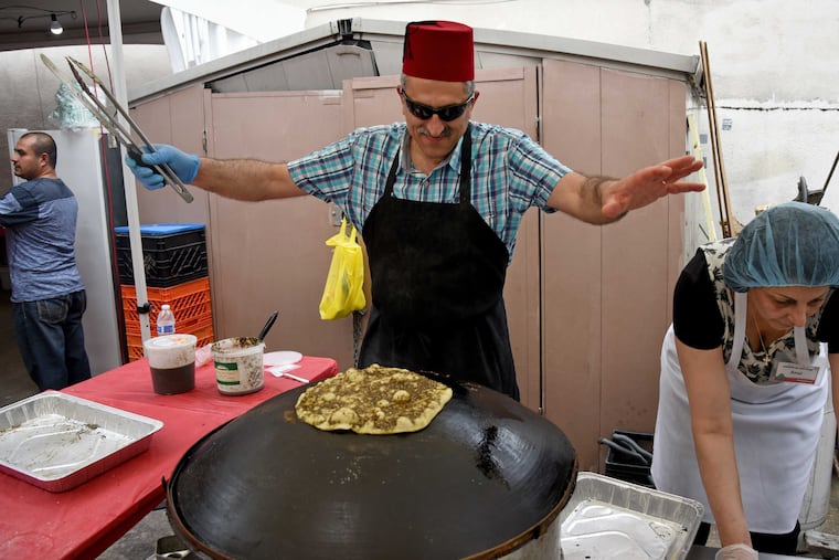 John Azzi dances to the music as he creates Za'atar manoush (sometimes called Lebanese pizza, at the Lebanese Festival at Saint Maron's Maronite Catholic Church in South Philadelphia June 4, 2017.