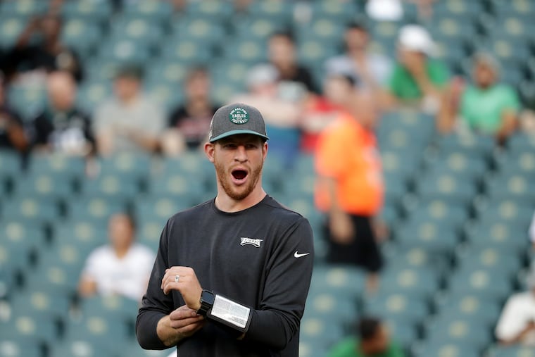 Eagles quarterback Carson Wentz yawns as he watches his teammates warm up before they played the Titans on Thursday.