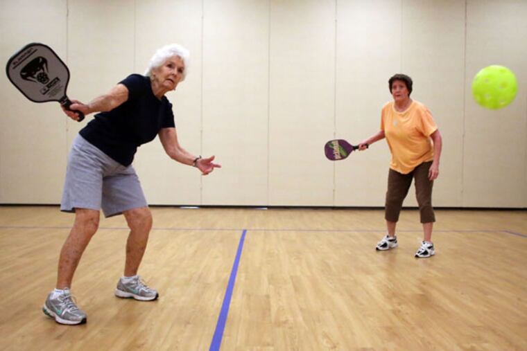Jay Massey, left, returns a volley as her teammate Betty Bailey watches as they play pickleball at the Five Points Center for Active Adults in Raleigh, North Carolina, on August 7, 2013. Pickleball is a racquet sport that combines elements of badminton, tennis and table tennis. (Al Drago/Raleigh News & Observer/MCT)