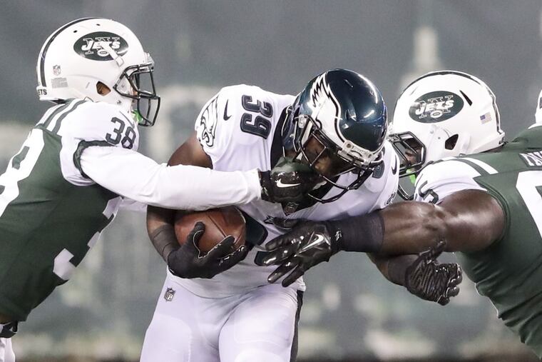 Eagles running back Byron Marshall gets his face mask grabbed by Jets cornerback Xavier Coleman (left) and stopped by defensive tackle Jeremy Faulk during the Eagles 16-10 loss to the Jets.