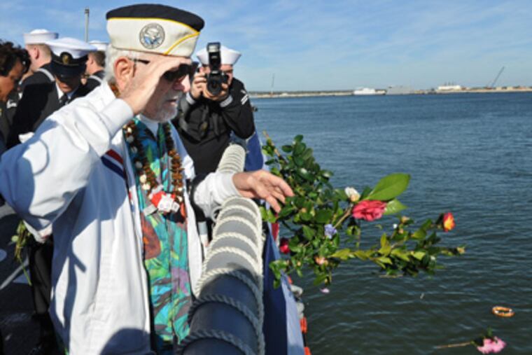 Pearl Harbor survivor Ed Kmiec salutes as he throws flowers over the rail during a remembrance ceremony, in Jacksonville, Fla.
