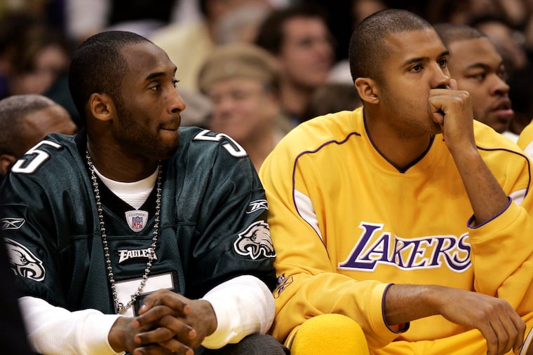 Kobe Bryant, left, wears an Eagles jersey, while sitting next to Lakers teammate Brian Cook during a February 2005 game against the San Antonio Spurs. Bryant was out with an ankle injury, but made sure to support the Birds ahead of their Super Bowl XXXIX matchup against the Patriots.