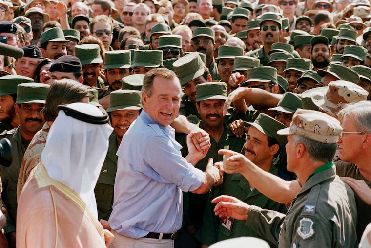 FILE - In this Nov. 22, 1990 file photo, President George H.W. Bush is greeted by Saudi troops and others as he arrives in Dhahran, Saudi Arabia, for a Thanksgiving visit. Bush died at the age of 94 on Friday, Nov. 30, 2018, about eight months after the death of his wife, Barbara Bush. (AP Photo/J. Scott Applewhite, File)