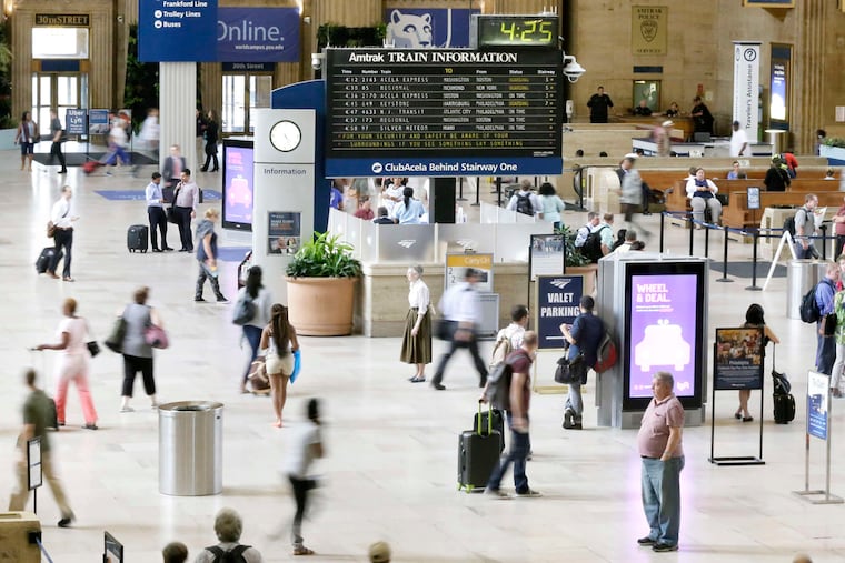Travelers make their way through 30th Street Station under the long-familiar flip board listing train departures.