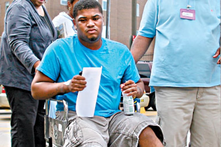 Khiry Caldwell, 18, shot after Strawberry Mansion High's commencement at Temple University, leaves the hospital with his parents, Kathy and Amin. (NEAL SANTOS / Inquirer Staff Photographer)