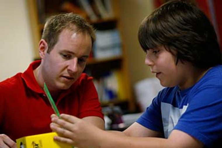 Cherry Hill teacher Scott Goldthorp, 28, whose lack of seniority puts him at risk, helps Dylan Solden, 12, measure volume. (MICHAEL S. WIRTZ / Staff Photographer)