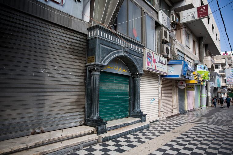 Palestinians walk next to closed shops in Gaza City, Tuesday, June 25, 2019, during a general strike against this week's economic conference in Bahrain that will kick off the Trump administration's plan for Mideast peace. (AP Photo/Khalil Hamra)