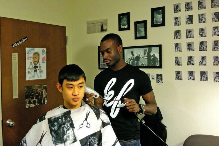 a construction-management major, cuts the hair of friend and fellow Drexel student John Tan. Behind them is his Wall of Fame of customers. SHAJ MATHEW / Staff