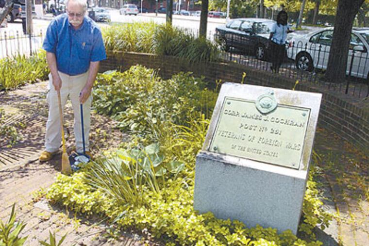 Joel Spivak sweeps trash in a small veterans park at the corner of 37th Street and Lancaster Avenue. (Ron Tarver / Staff Photographer)