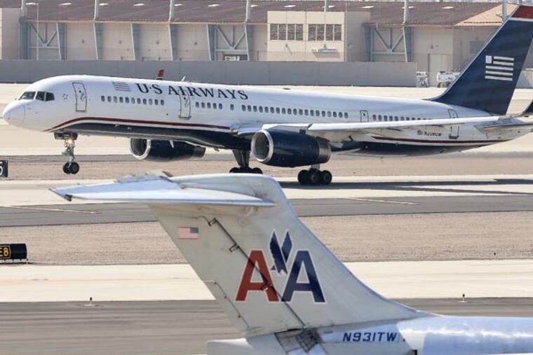 FILE - In this Thursday, Feb. 14, 2013, file photo, a U.S. Airways jet passes an American Airlines jet at Sky Harbor International Airport in Phoenix. The merger of the two airlines has given birth to a mega airline with more passengers than any other in the world. The Justice Department and a number of state attorneys general on Tuesday, Aug. 13, 2013, challenged a proposed $11 billion merger between US Airways Group Inc. and American Airlines' parent company, AMR Corp. (AP Photo/Matt York, file)