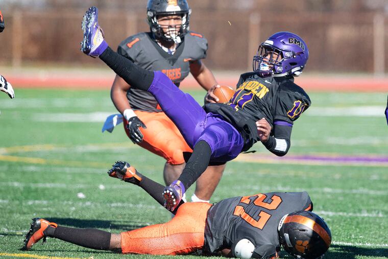 Camden High School quarterback Monte Williams is tackled by Woodrow Wilson's Jahdir White (on ground) while the Tigers' Muheem McCargo closes in the play during the annual Thanksgiving Day game rivalry in 2018.
