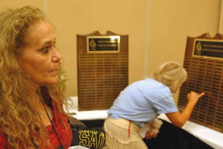 Deborah Cunningham, left, of Dexter, Maine, reads names on panels of
the "Murder Wall" last night. The wall remembers the slain children of members of the Parents of Murdered Children. Cunningham's 21-month-old grandson was killed in 1999. (Tom Gralish / Staff Photographer)