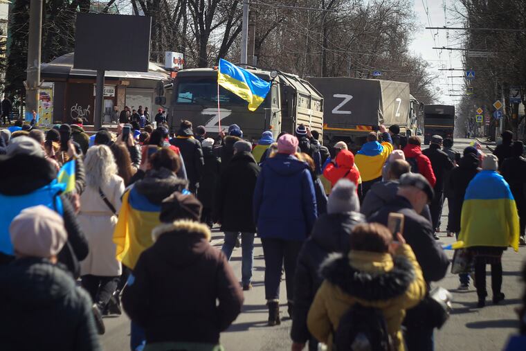 People with Ukrainian flags walk towards Russian army trucks during a rally against the Russian occupation in Kherson, Ukraine, Sunday, March 20, 2022.