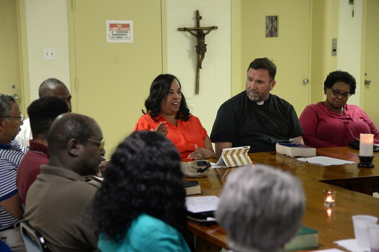Jacquelyn Washington (left) talks about the Confederate battle flag as the Rev. Chris Walsh opens a Bible study at St. Raymond of Penafort. TOM GRALISH / Staff Photographer