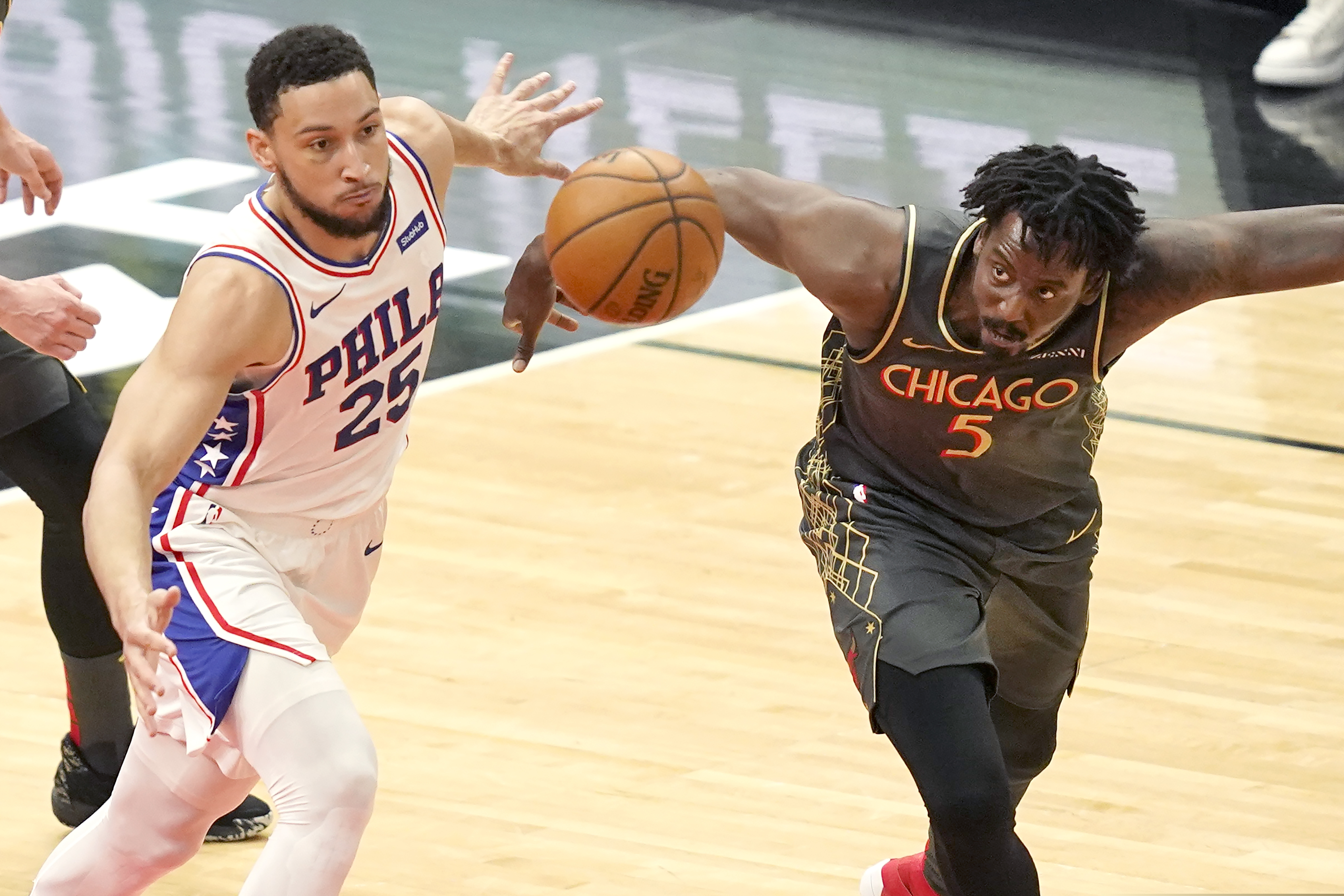 The 76ers' Ben Simmons and Al-Farouq Aminu (5) of the Bulls keep their eyes on a loose ball during the first half in Chicago.