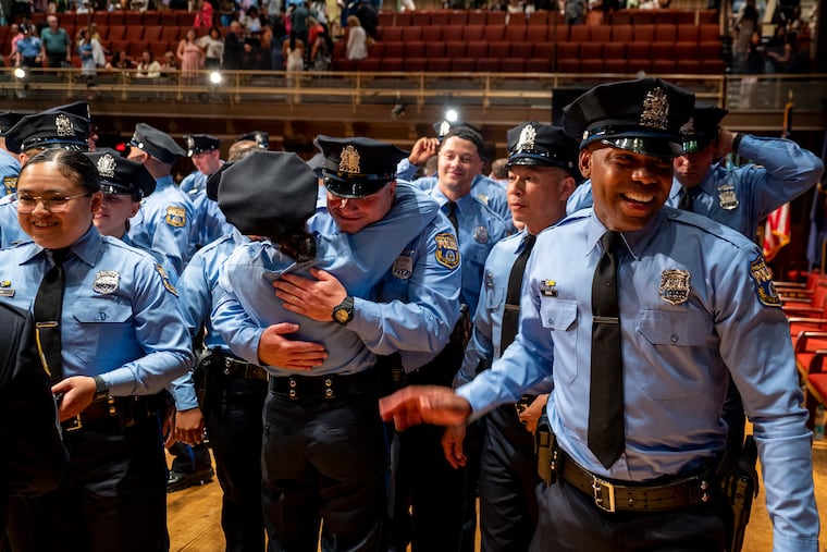 New officers, members of the police academy Class #402 of the Philadelphia Police Department and Temple University Police Department, congratulate each other following graduation ceremonies in June 2024. Officers will wear dark blue shirts starting in the fall.