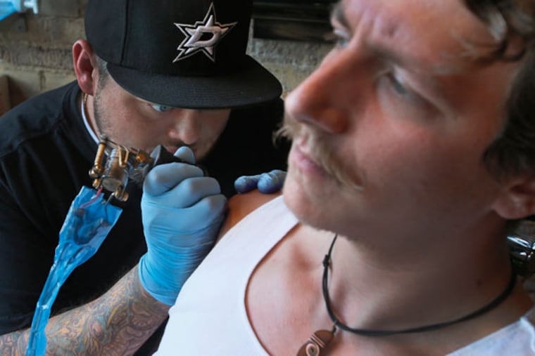 Tattoo artist Cody Biggs works on a tattoo on the arm of Adam Metzger in Dallas on May 15, 2014. Experts advise making sure you are up to date on your immunizations, especially hepatitis and tetanus, before getting a tattoo. (Louis DeLuca/Dallas Morning News/MCT)