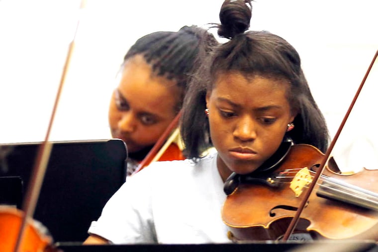 Violinist Kashay Fogle (right) plays her violin while Philadelphia Orchestra Music Director Yannick Nézet-Séguin rehearses the first movement of Mozart's "Eine Kleine Nachtmusik" ("A Little Nightmusic") at the St. Francis de Sales School on Wednesday, April 23, 2014. The students will perform, while conducted by Nézet-Séguin at Verizon Hall at the Kimmel Center on Friday, April 25, 2014. Fogle is a seventh-grader at the St. Frances de Sales School in West Philadelphia.