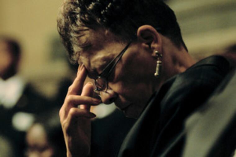 Cynthia Wilson bows her head during a prayer at Samuel L. Evans' memorial service at City Hall.