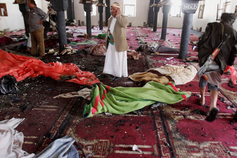Bodies covered with blankets lie in a mosque as people stand around after an attack Friday in the Yemen capital.