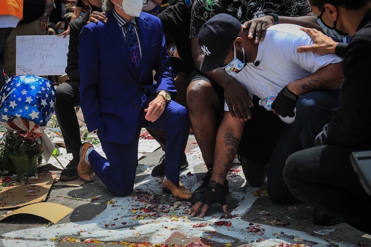 An emotional Terrence Floyd, second from right, is comforted as he touch the spot at the intersection of 38th Street and Chicago Avenue, Minneapolis, Minn., where his brother George Floyd, encountered police and died while in their custody.