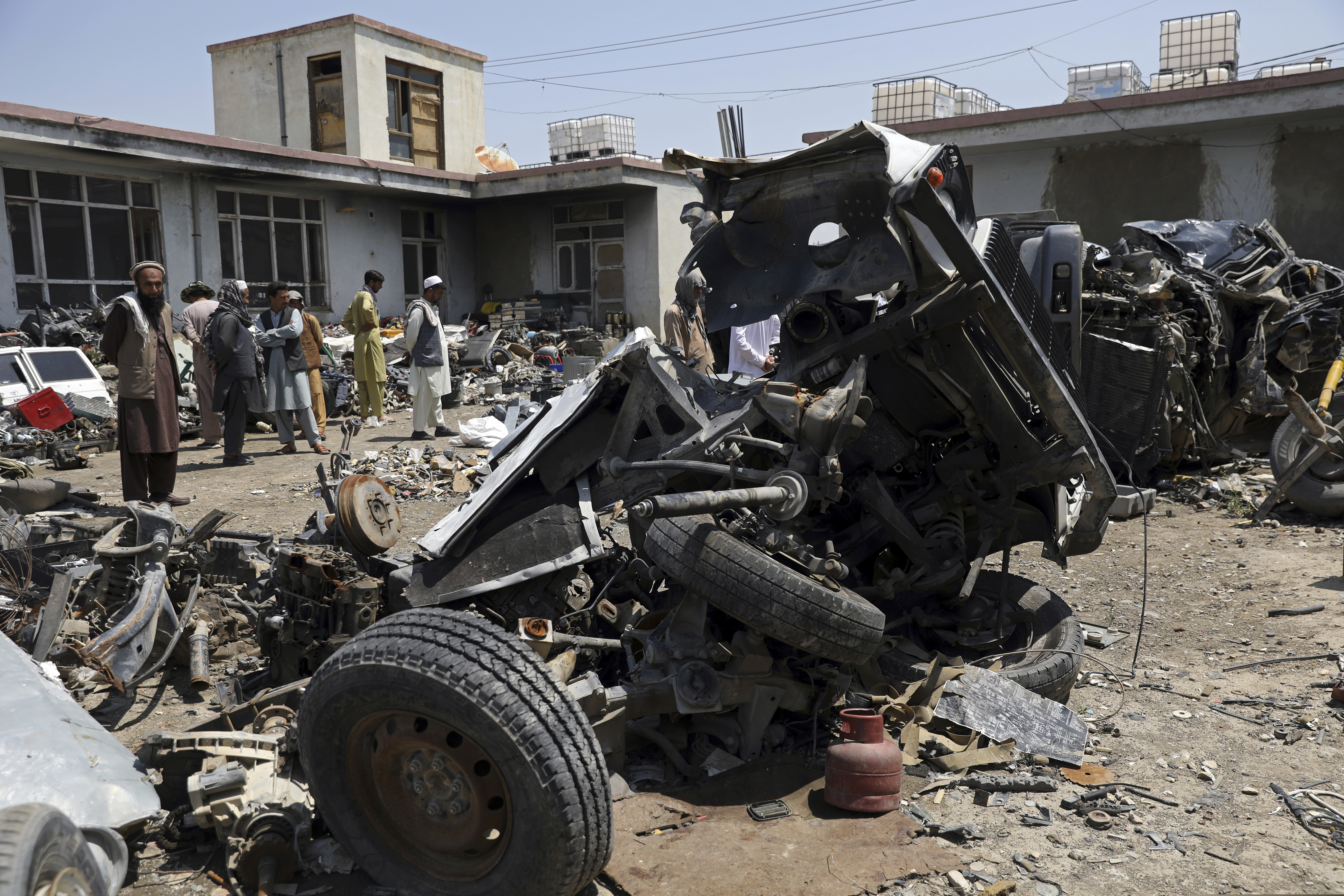 Afghans stand inside Baba Mir's scrapyard outside Bagram Air Base, northwest of the capital Kabul, Afghanistan, Monday, May 3, 2021. As US troops pack up to leave Afghanistan after nearly 20 years of war, it's trashing tons of equipment and selling it as scrap to local dealers. Among Afghans it is causing anger that the mountain of supplies and equipment was trashed before being sold to them.