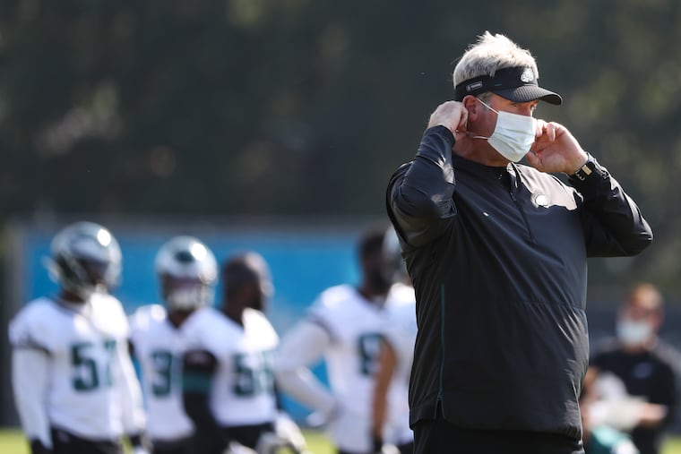 Eagles head coach Doug Pederson puts on his mask during practice on Wednesday.