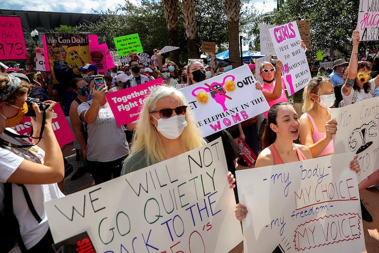 Participants wave signs as they walk back to Orlando City Hall during the March for Abortion Access, Oct. 2, 2021, in Orlando, Fla.