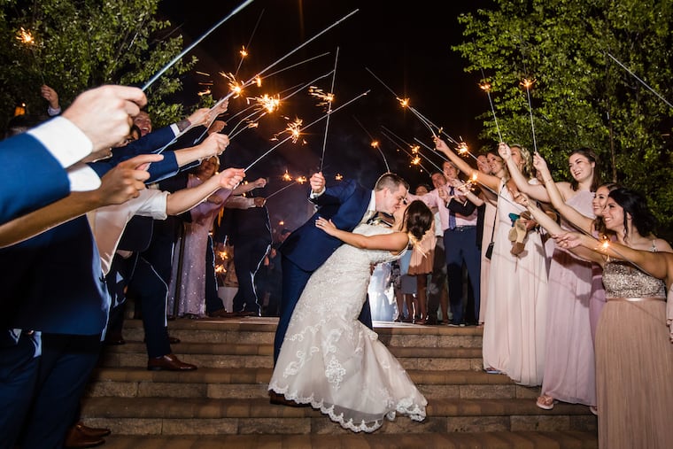 Alyson Ragone and John Demas walking through a sparkler arch made by their wedding party.
