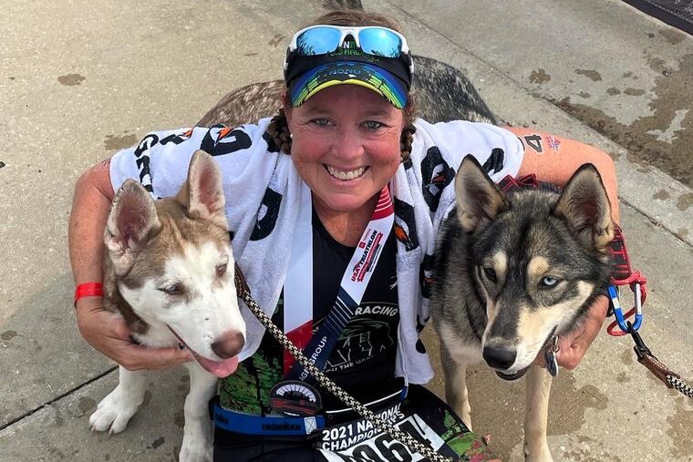 Jill Walker poses with two dogs after finishing a triathlon in Milwaukee in August 2021. MUST CREDIT: Courtesy of Jill Walker