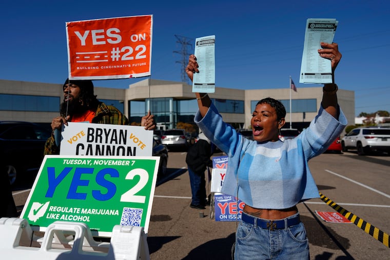 Nikko Griffin, left, and Tyra Patterson, call out to arriving voters in the parking lot of the Hamilton County Board of Elections in Cincinnati. They urged people to vote for different issues, including Issue 2, which would allow adult-use sale, purchase, and possession of cannabis for Ohioans who are 21 and older.