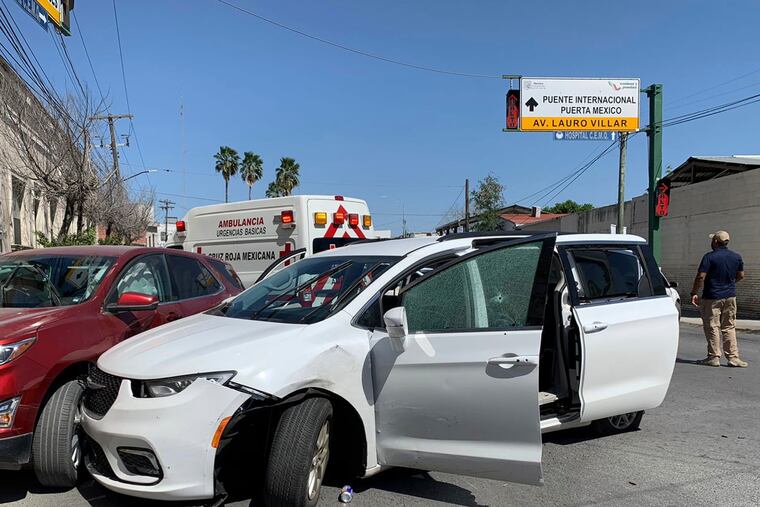 A member of the Mexican security forces stands next to a white minivan with North Carolina plates and several bullet holes, at the crime scene where gunmen kidnapped four U.S. citizens who crossed into Mexico from Texas on Friday.