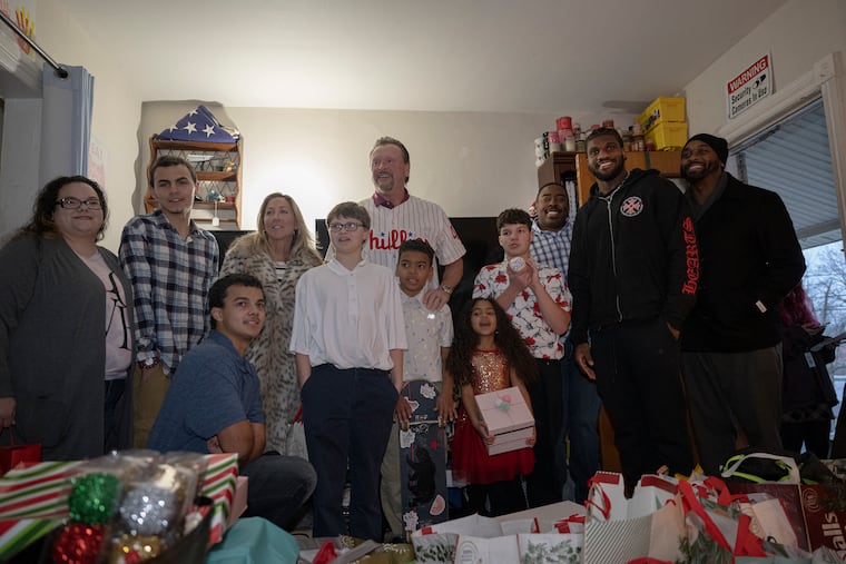 Former Philadelphia Phillies pitcher Tommy Greene, center, and New York Jets tight end Kenny Yeboah, second from right, pose with the Miller-Wilson family’s six children during a Christmas gift surprise at their home in Coatesville..