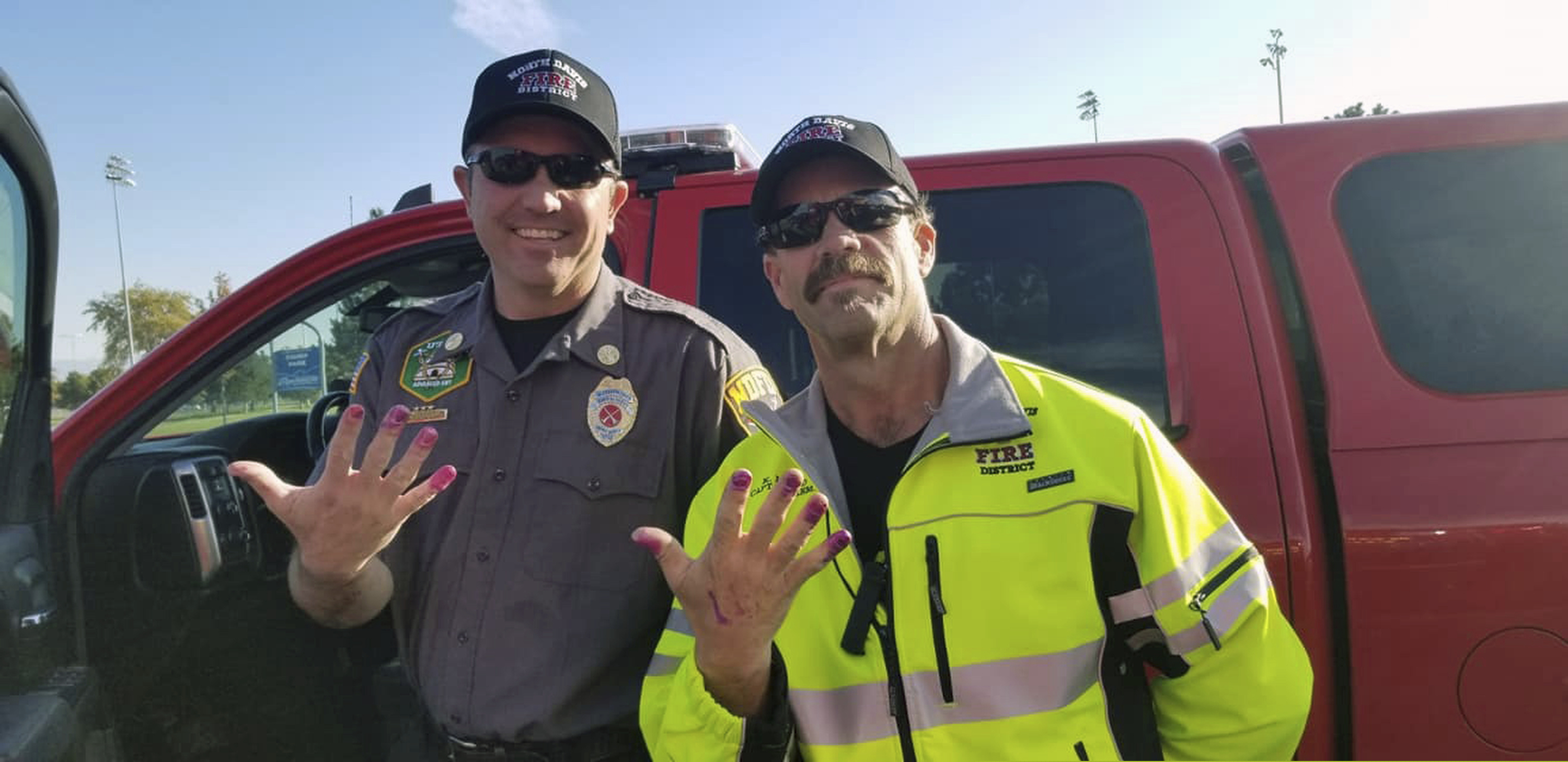 This Friday, Oct. 11, 2019, photo released by the North Davis Fire District shows Chief Allen Hadley, left, and Cpt. Kevin Lloyd In Clearfield, Utah. The two Utah firefighters are receiving praise after they found a creative way to keep a young girl calm at the scene of a car accident. North Davis Fire District Fire Chief Mark Becraft said the firefighters let a young girl paint their nails after she and her mother were in a car accident Saturday. Chief Hadley and Cpt. Lloyd checked on the crying and screaming girl while medics evaluated her mother. Nobody was seriously injured.