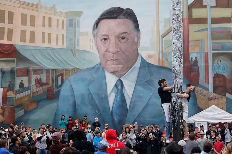 May 21, 2016: Participants try to climb the greased pole with the mural of former Philadelphia Mayor Frank Rizzo looking on at the South 9th Street Italian Market Festival.